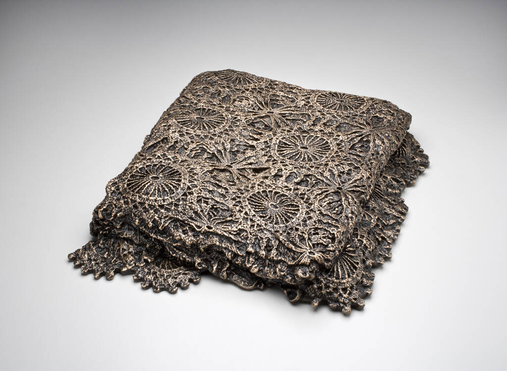 Bronze casting of folded vintage crocheted blanket with a floral design.